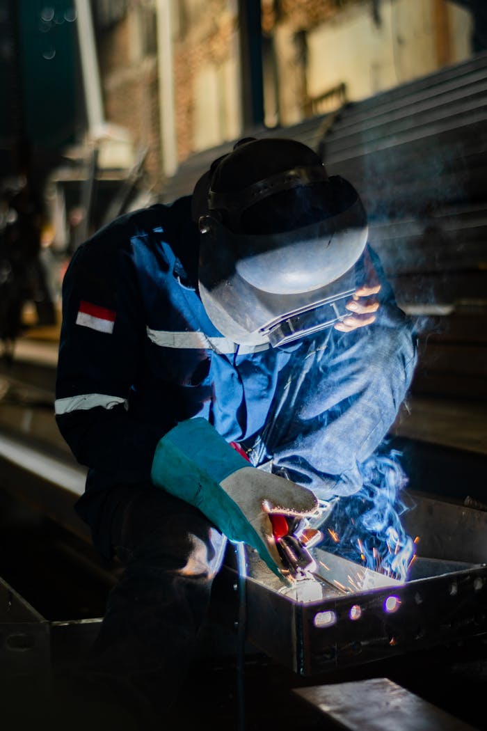 A skilled welder working with sparks in an industrial factory environment.